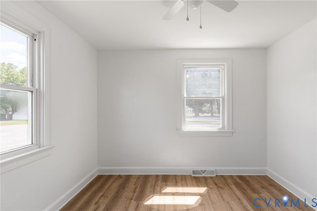 Bright interior with two windows, wood-finish flooring, and a ceiling fan