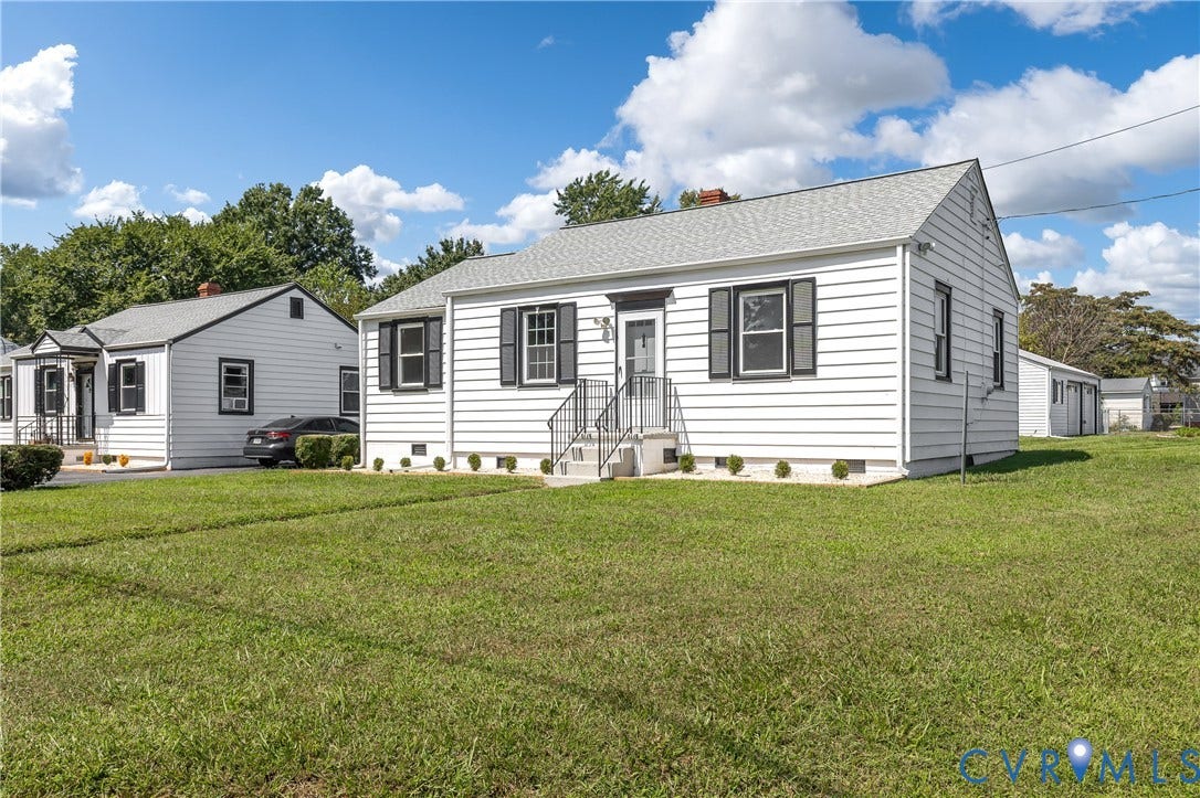 White siding exterior with black shutters, a gabled roof, and a front entry porch with metal railing