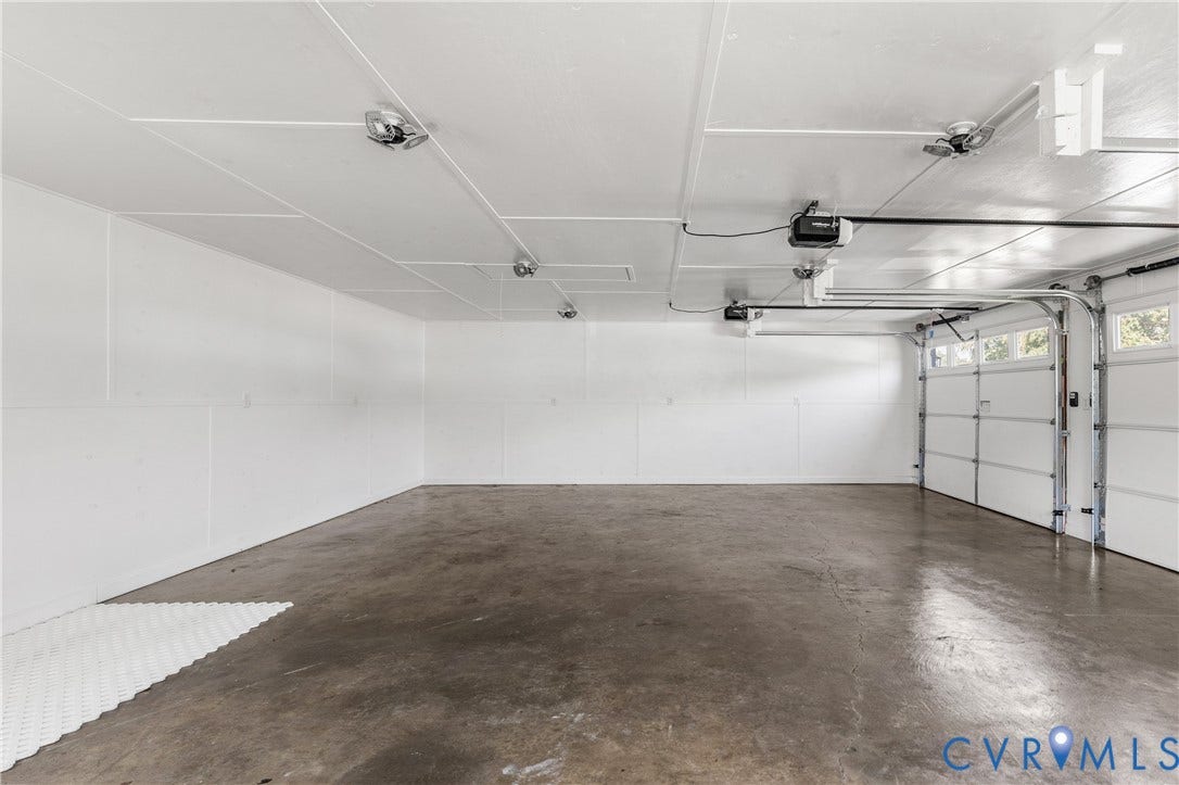 Two-car garage featuring a concrete floor, white panel walls, and two garage door openers