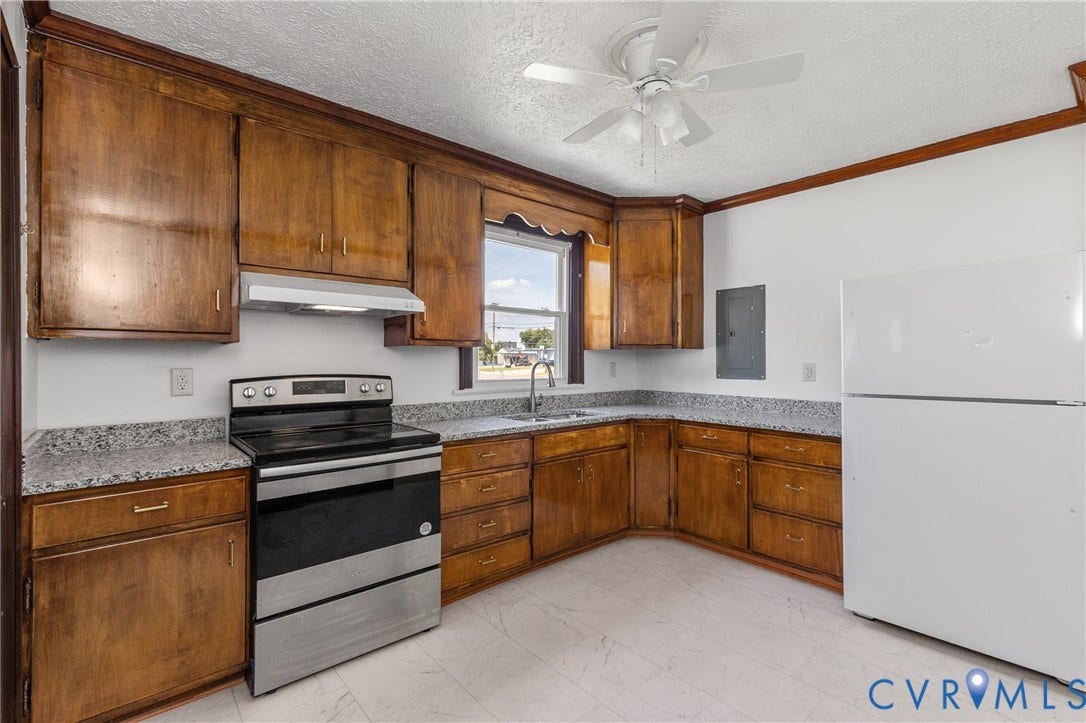 Kitchen featuring wood cabinetry, light-toned countertops, a stainless steel range, and a ceiling fan