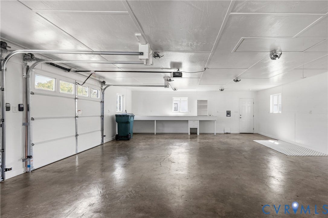 Garage space featuring a concrete floor, multiple windows, a workbench with built-in cabinetry, and overhead lighting