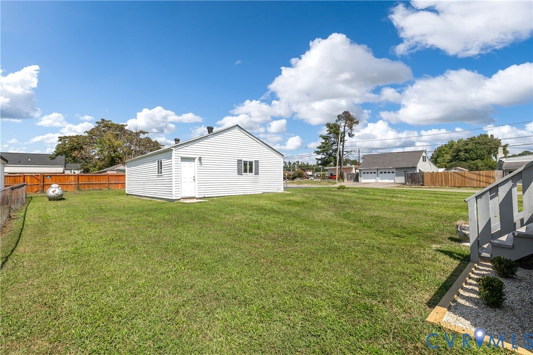 Spacious residential lot featuring a single-story home with vinyl siding exterior, situated on manicured lawn grounds with mature landscaping
