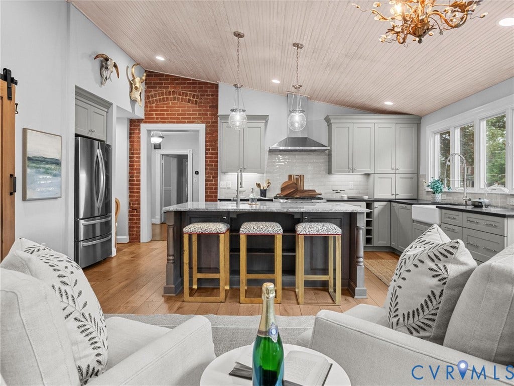3403 W Franklin Street, Museum District, Richmond, VA 23221 Kitchen featuring an angled wood-paneled ceiling, stainless steel appliances, a center island with pendant lighting, a farmhouse sink, and a brick wall accent