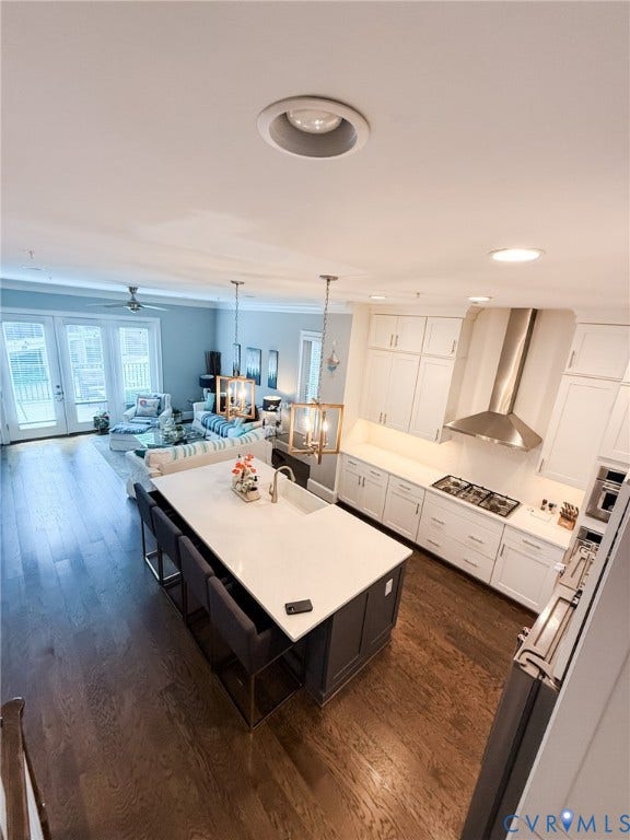 3332 Haydenpark Lane, Henrico, VA 23233 Open-concept living space with wood-finish flooring, white kitchen cabinetry, a large kitchen island with seating, a gas cooktop, and French doors leading to an outdoor area