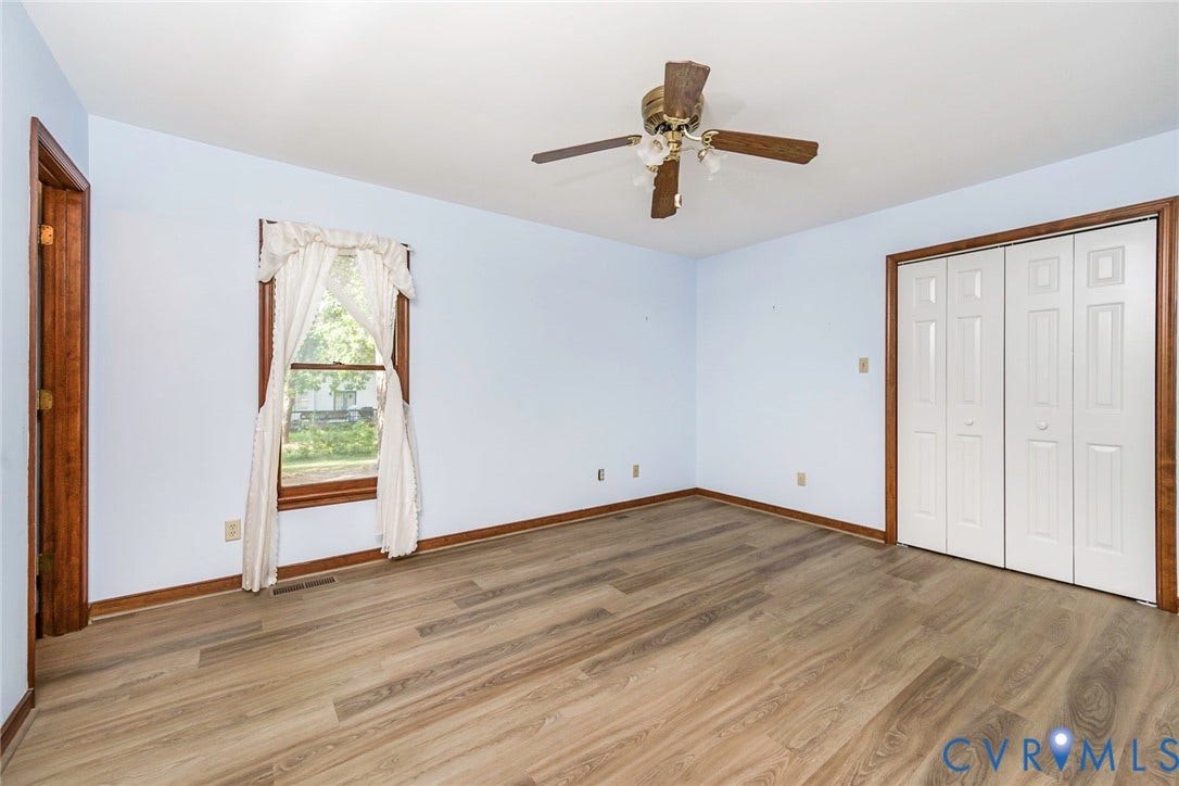 Wood-finish flooring throughout, ceiling fan with light fixture, and a built-in bi-fold door closet