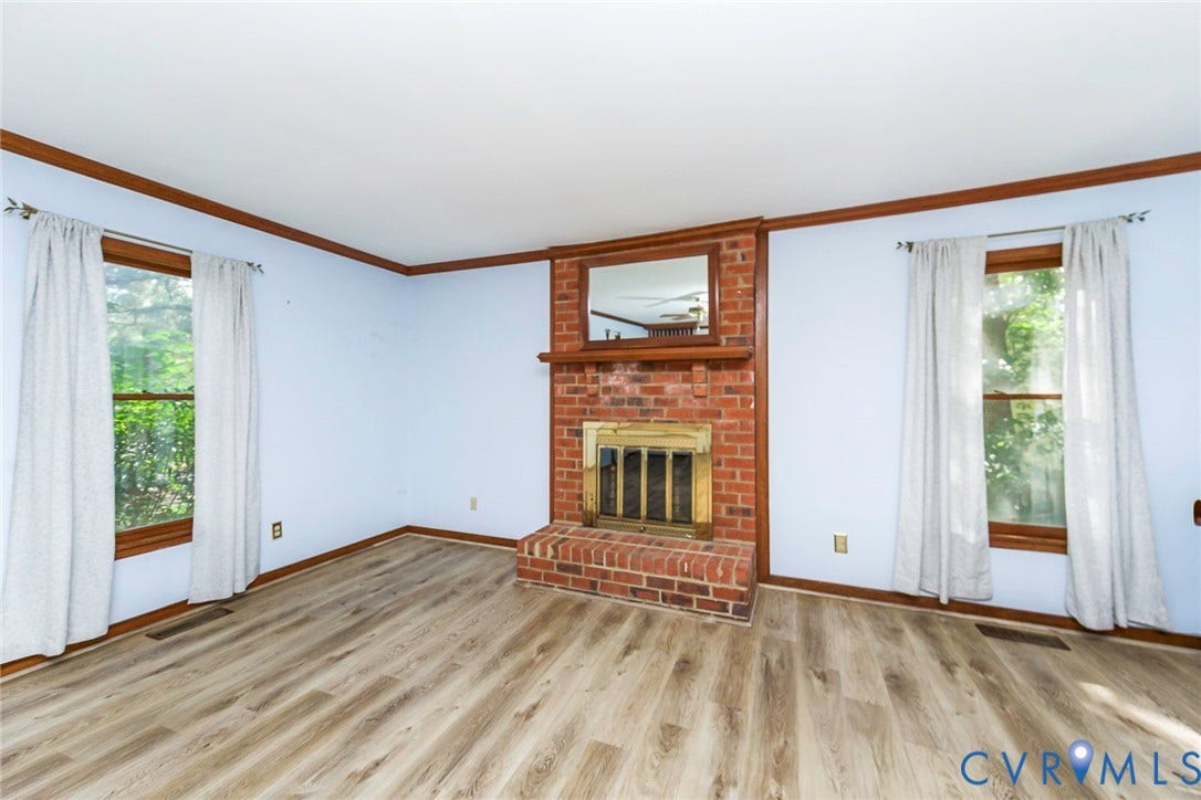 Brick fireplace with wood mantel, wood-finish flooring, and crown molding