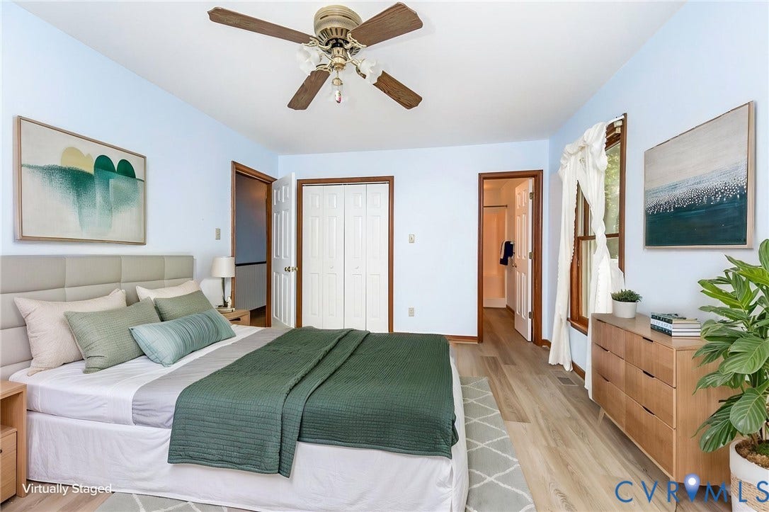 AI STAGED Light wood-finish flooring with a ceiling fan, a window with wood trim, and bi-fold closet doors