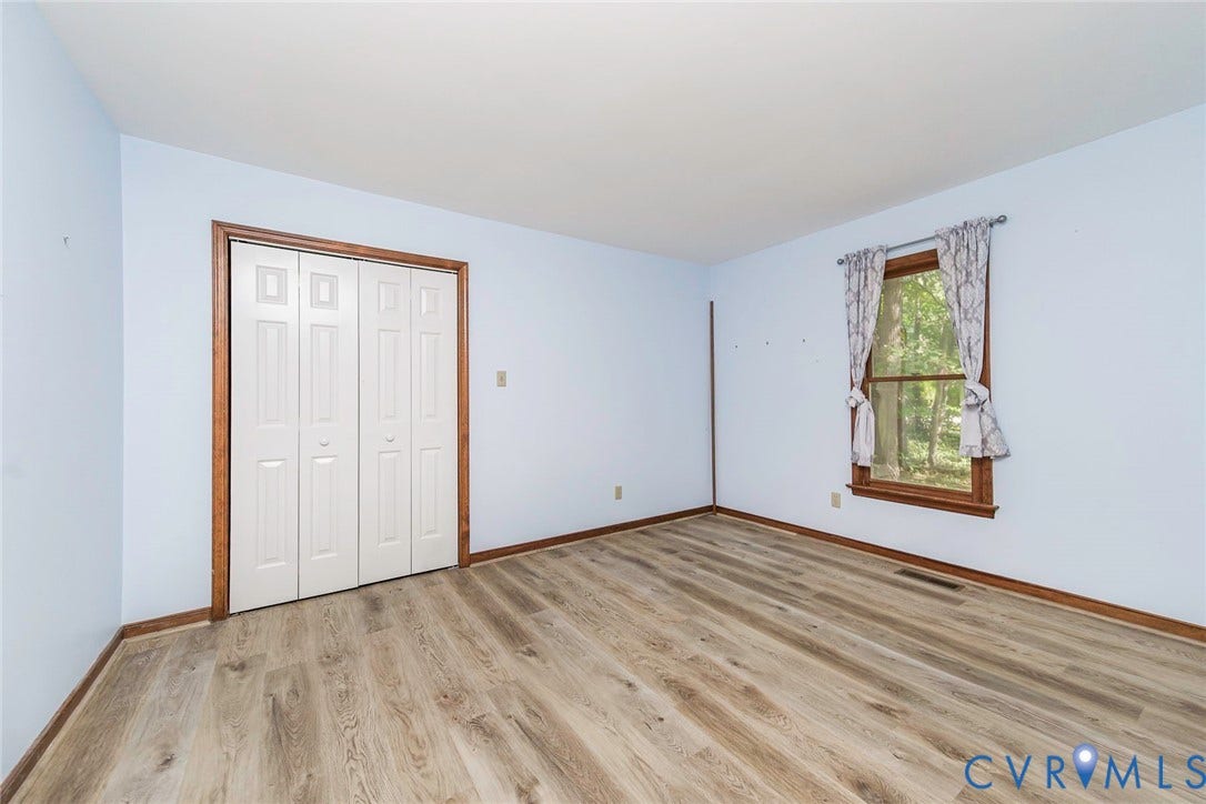 Wood-finish flooring, white bi-fold closet doors, and a window with wood trim