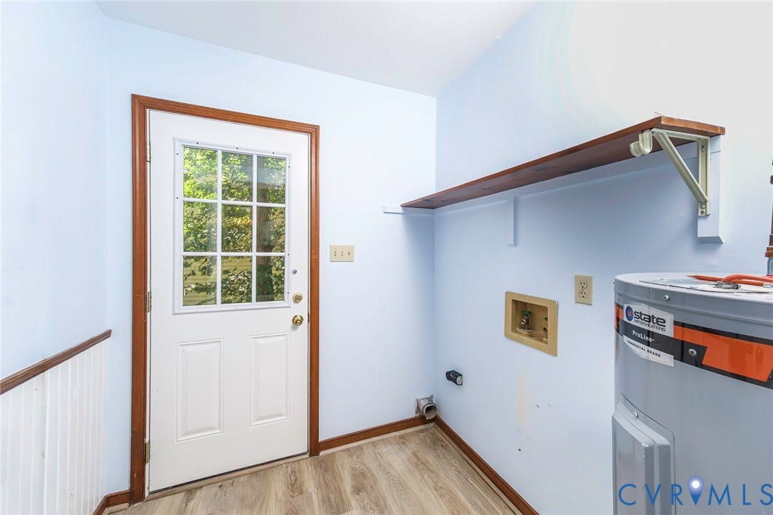 Wood-finish flooring, white paneled door with window, and a built-in wood shelf