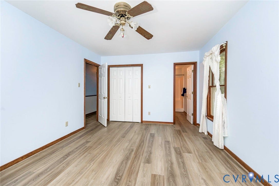 Wood-finish flooring, ceiling fan with light fixture, double bi-fold closet doors, and wood-framed window