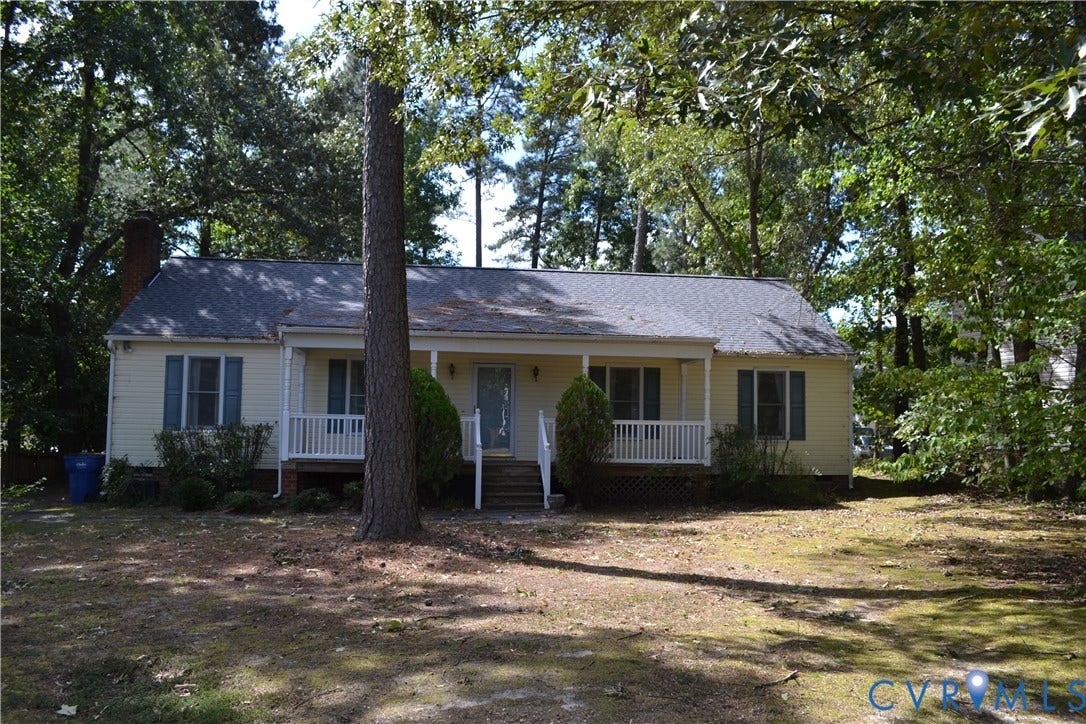 Charming ranch-style home featuring a covered front porch with white railings, composite siding exterior, and a pitched roof