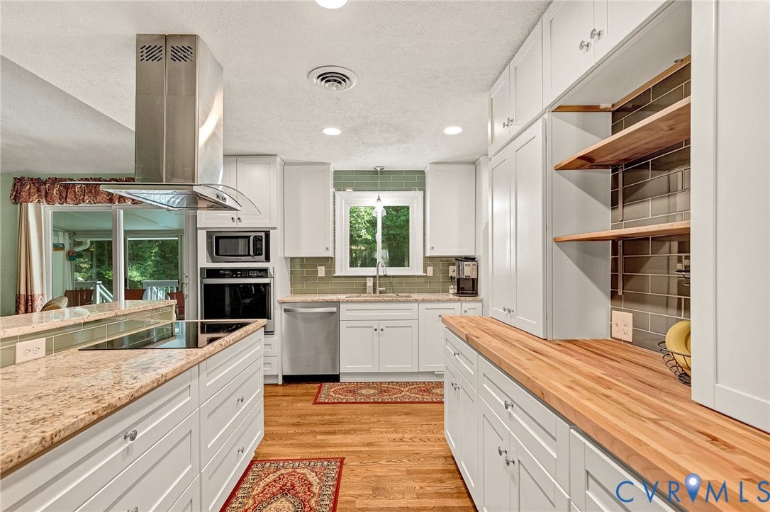 Kitchen featuring white cabinetry, wood-finish flooring, light-toned granite countertops, stainless steel appliances, and a tiled backsplash