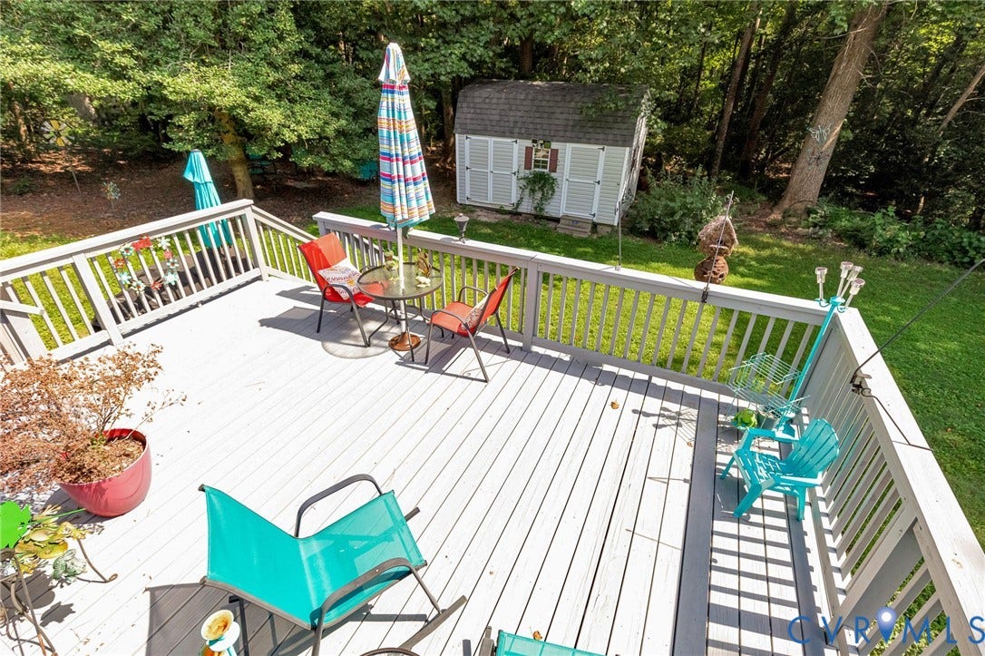 Expansive wood-finish deck with railing overlooking a green lawn