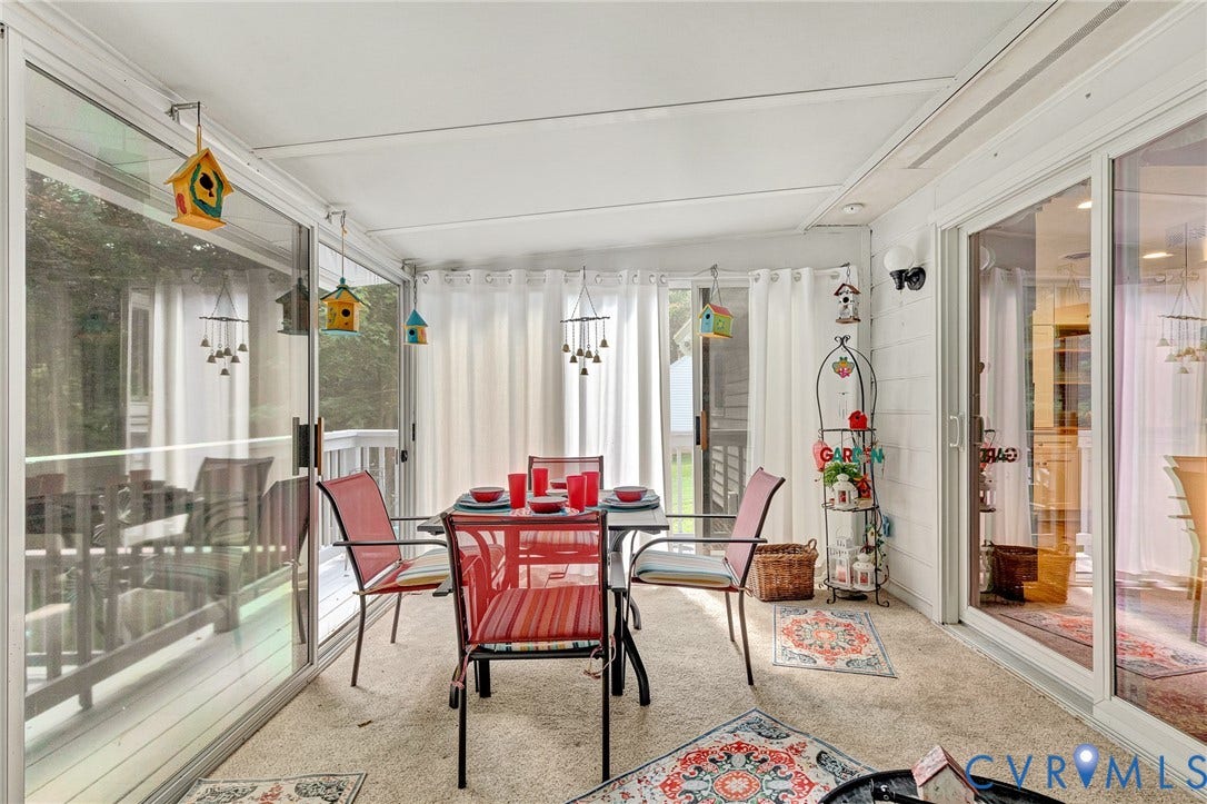 Enclosed patio featuring sliding glass doors, carpeted flooring, and a white paneled wall