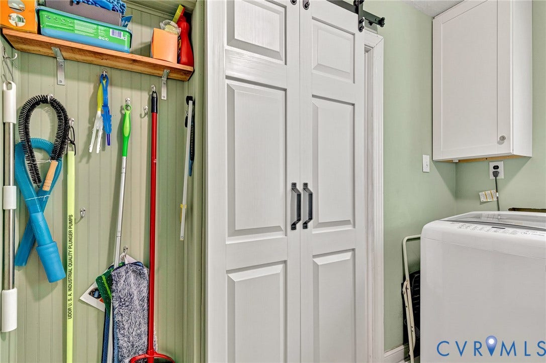 White paneled closet doors with black hardware, barn door-style track, and an integrated shelf with wall hooks