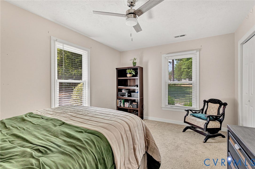 Carpeted flooring, white trim windows with blinds, and ceiling fan