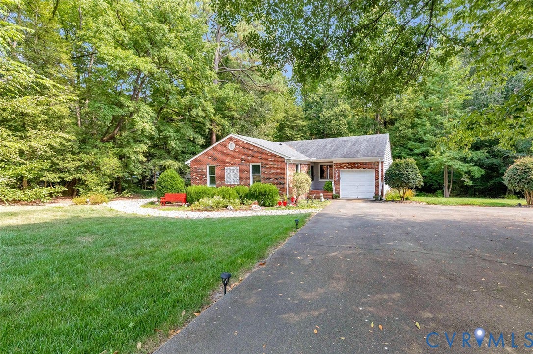 Brick exterior, attached garage, paved driveway, mature trees, landscaped front yard