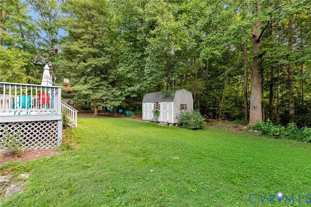 Expansive green lawn, multi-level wood deck with lattice skirting, and a storage shed with white shutters