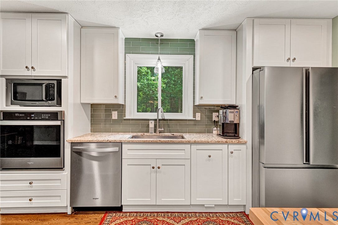 White shaker-style cabinetry with stainless steel appliances, granite countertops, and a subway tile backsplash