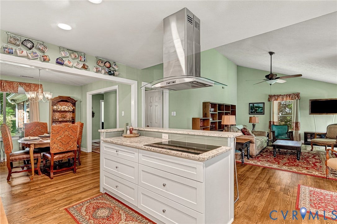 Kitchen island with a built-in cooktop, light-toned countertops, and a stainless steel range hood