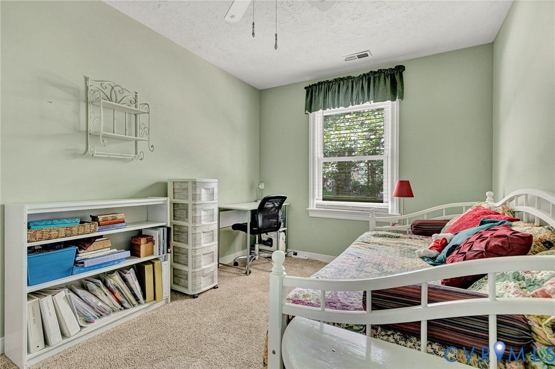 Carpeted interior with light green walls, a single window with blinds, and a ceiling fan