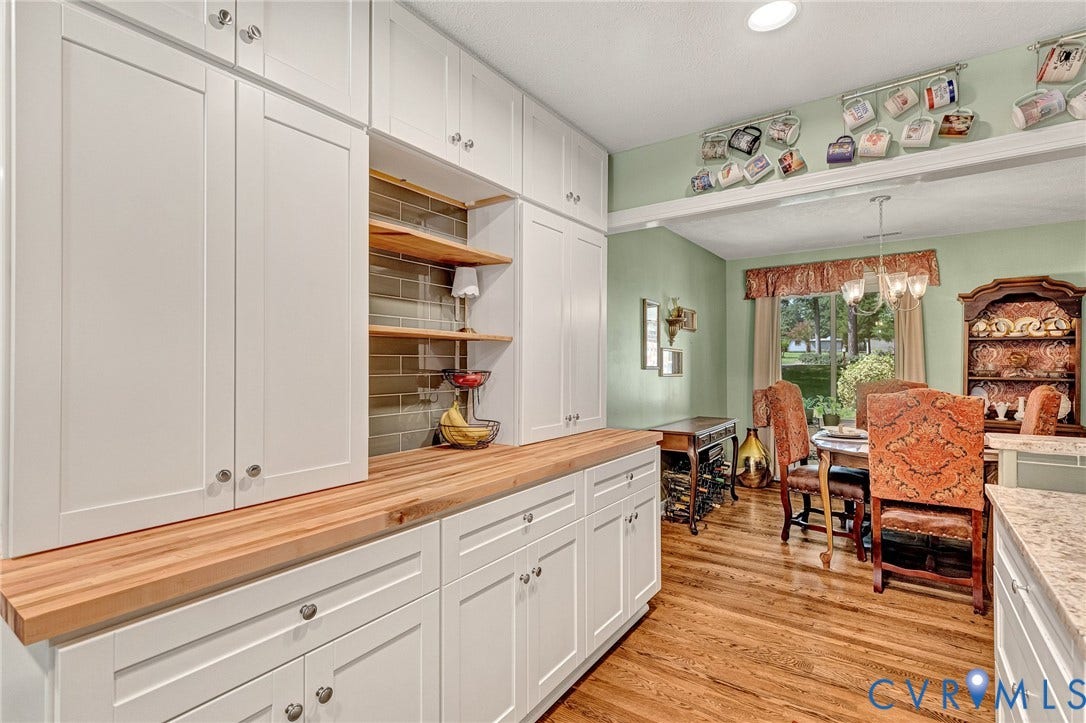 White cabinetry with brushed nickel hardware, natural wood countertops, open shelving with tile backsplash, and wood-finish flooring