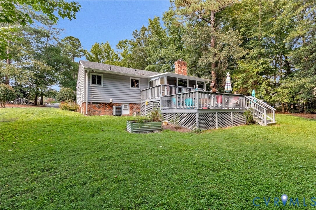 Expansive green lawn with a large wooden deck featuring lattice skirting and steps