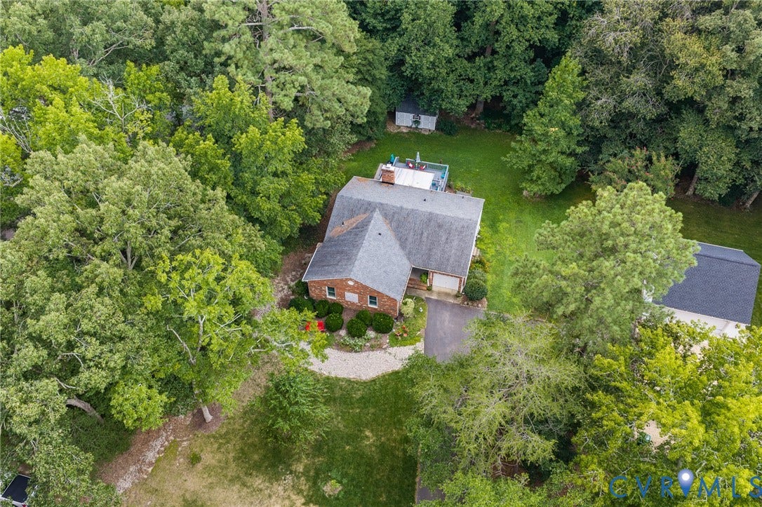 Brick exterior residence with a shingled roof, attached garage, and a paved driveway