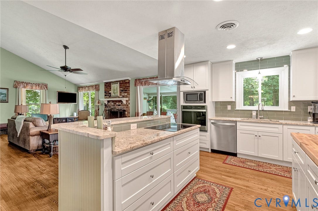 Kitchen featuring white cabinetry, light-colored countertops, stainless steel appliances, and a tile backsplash