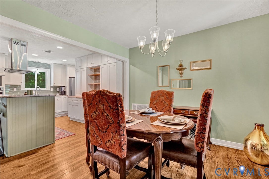 Hardwood flooring, overhead chandelier, recessed lighting, white cabinetry, and kitchen island with beadboard paneling
