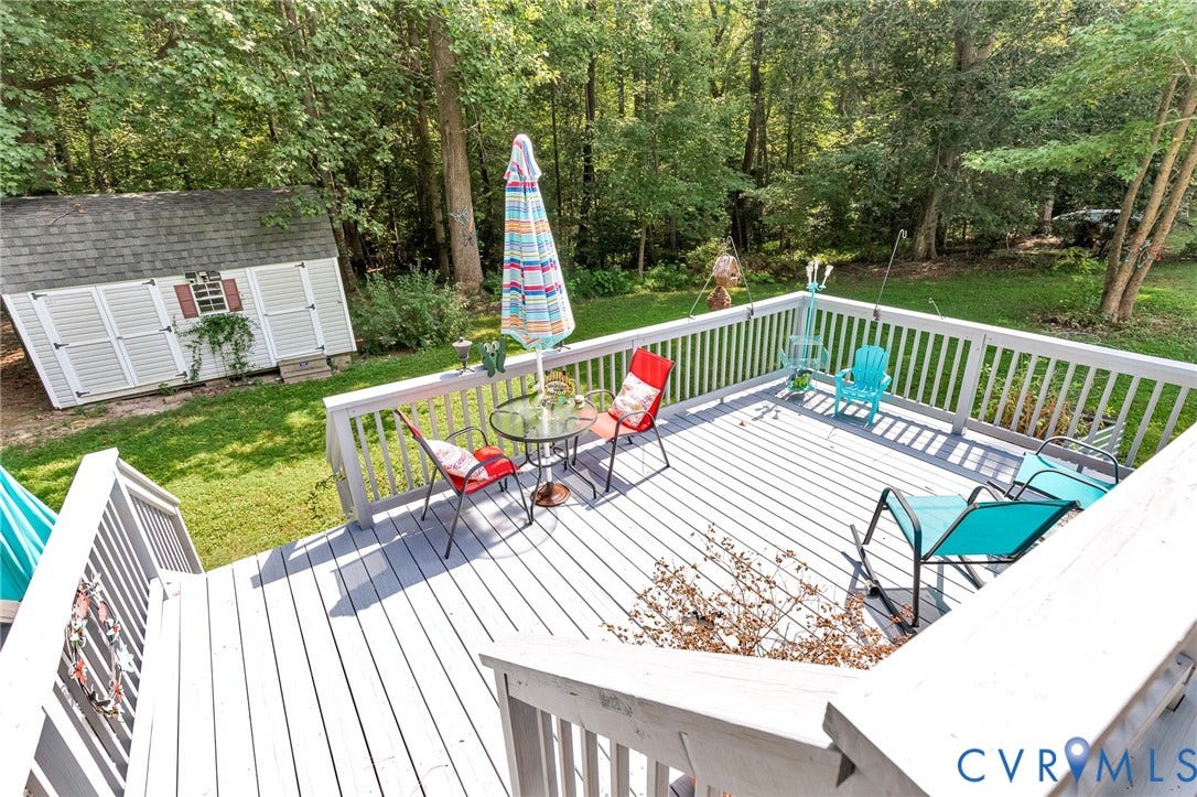 Expansive outdoor deck with white railing, overlooking a lush green yard and mature trees