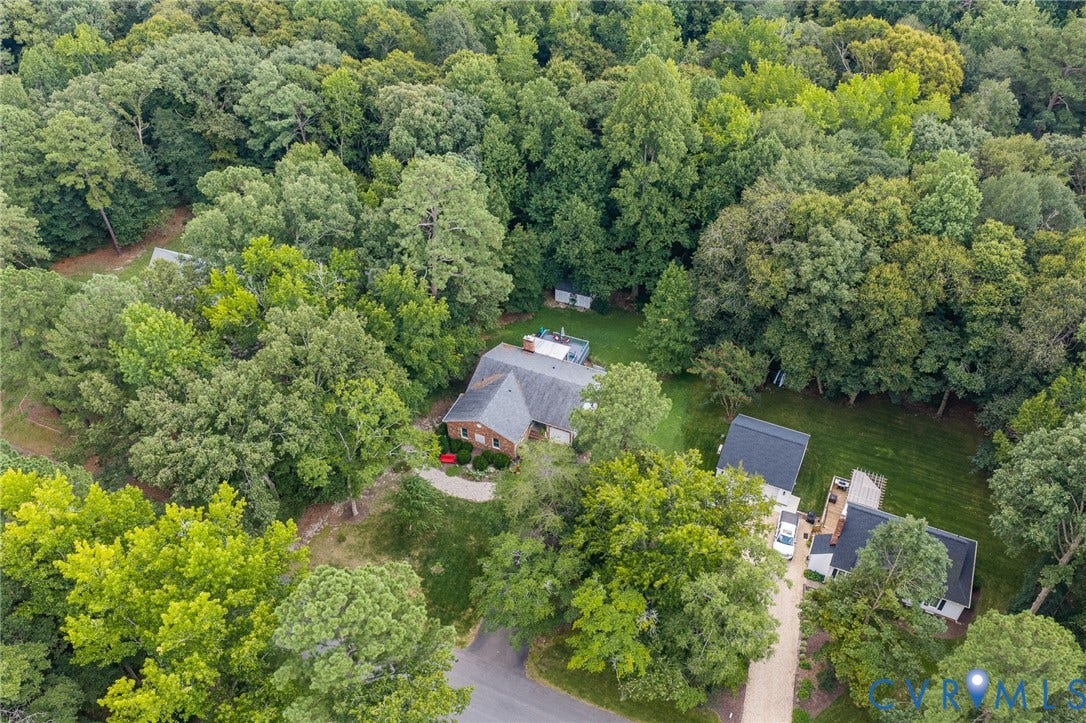 Expansive treed lot featuring a brick residence, secondary dwelling, and multiple detached structures