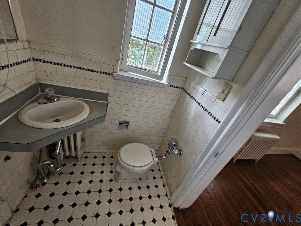 505 N Arthur Ashe Boulevard, #U3, Richmond, VA 23220 Bathroom featuring white subway tile walls with decorative border, built-in corner sink, patterned floor tile, and wall-mounted storage cabinet