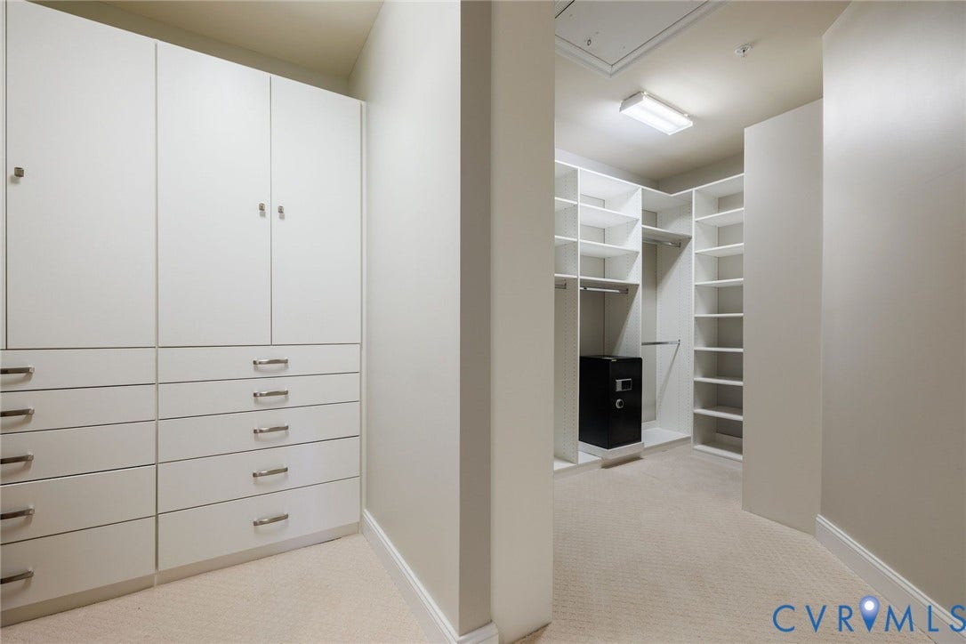 Primary Bedroom Large Walk-in Closet. Custom shelving and drawers.  Carpet.