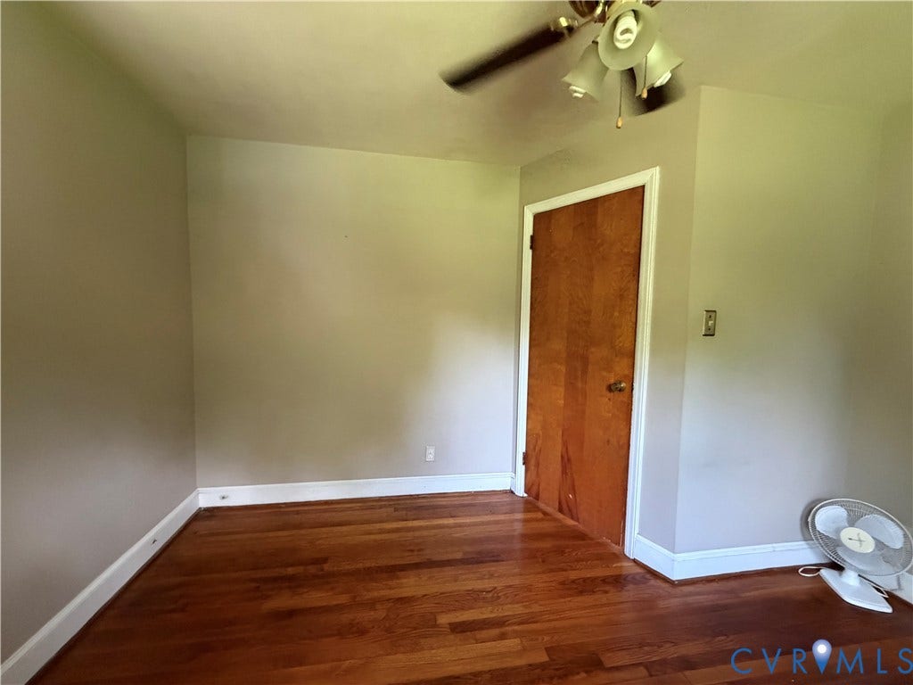 Hardwood flooring, neutral wall tones, wood-panel door, and a ceiling fan with integrated lighting