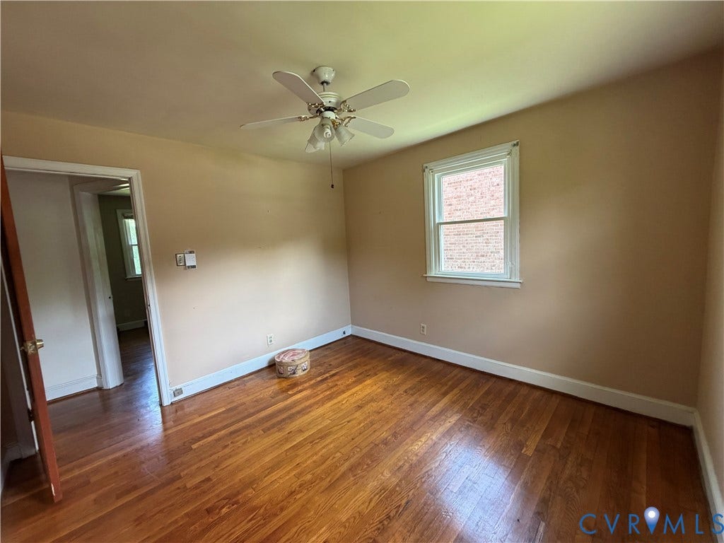 Hardwood flooring, neutral wall tones, ceiling fan with integrated lighting, and a double-hung window
