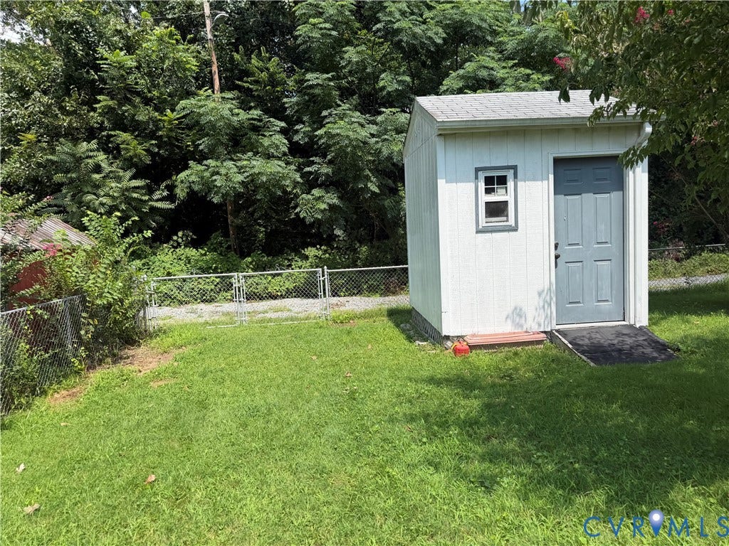 Detached storage shed with a panel door, a single-pane window, and a gray shingle roof