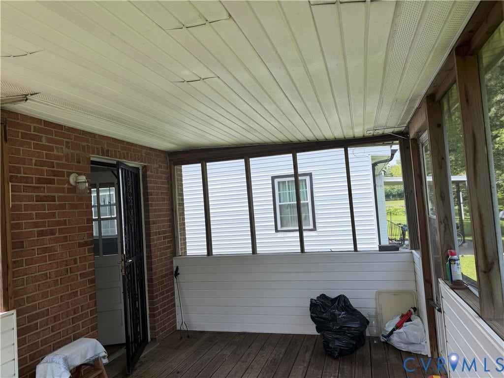 Enclosed porch featuring wood-finish flooring, brick exterior wall, and white paneling