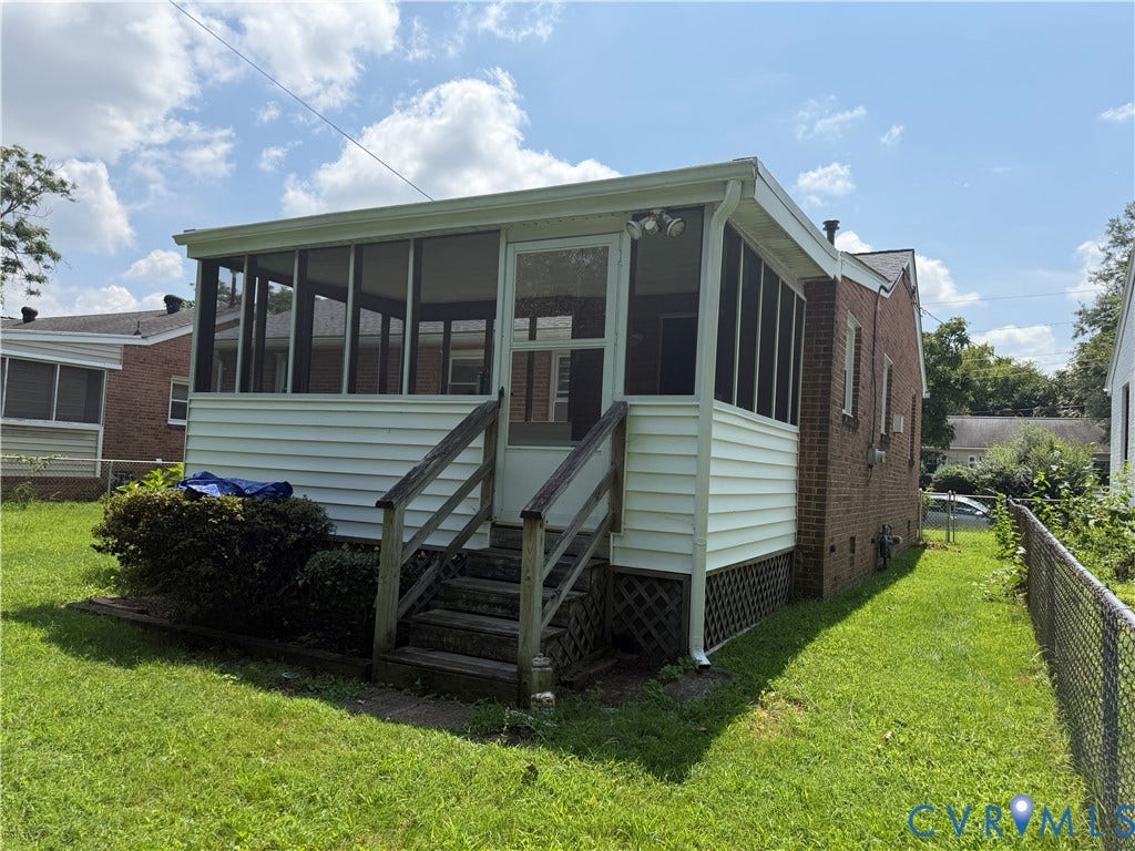 Screened porch with white siding and wood stairs, brick exterior, and a chain-link fence