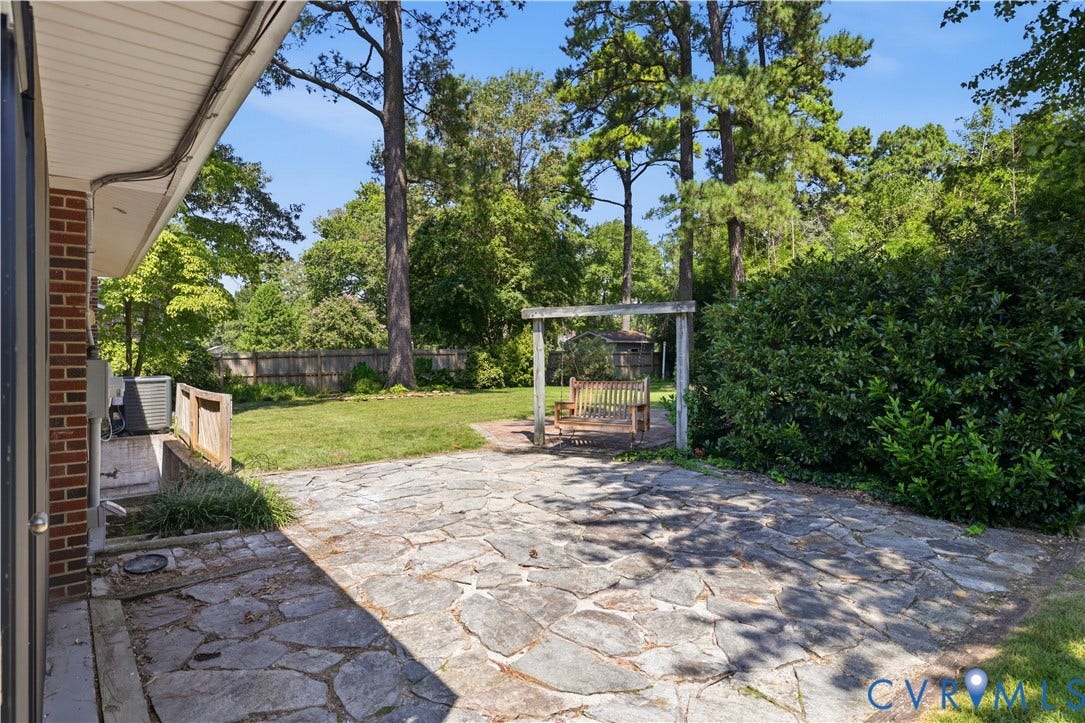 Screened porch, white siding, lush green lawn, mature trees, gravel patio area