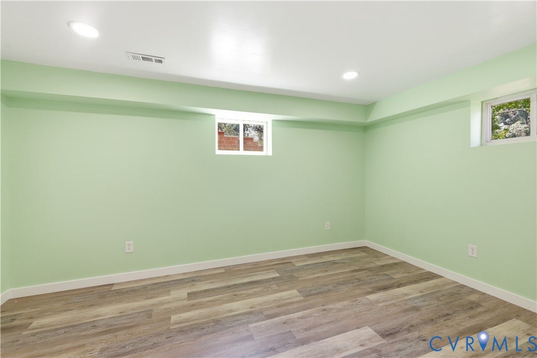 Bright, freshly painted 2nd primary room featuring soft sage-green walls, recessed ceiling lighting, and warm wood-finish flooring throughout