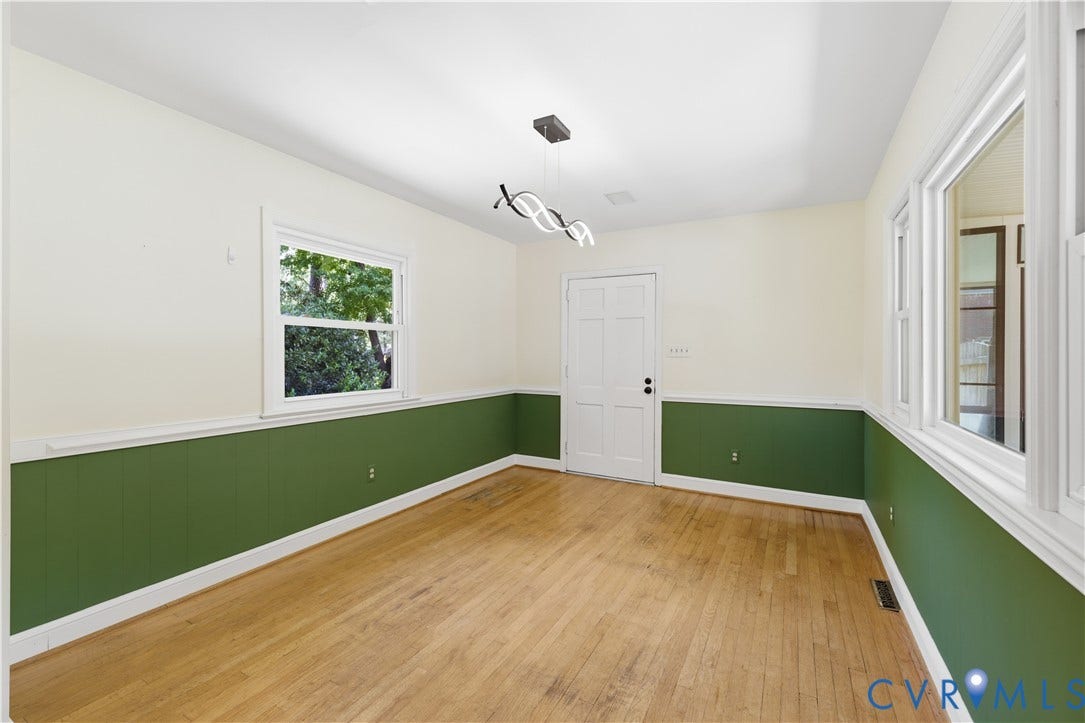 Hardwood flooring, modern ceiling light fixture, white trim, paneled interior door, and multiple windows