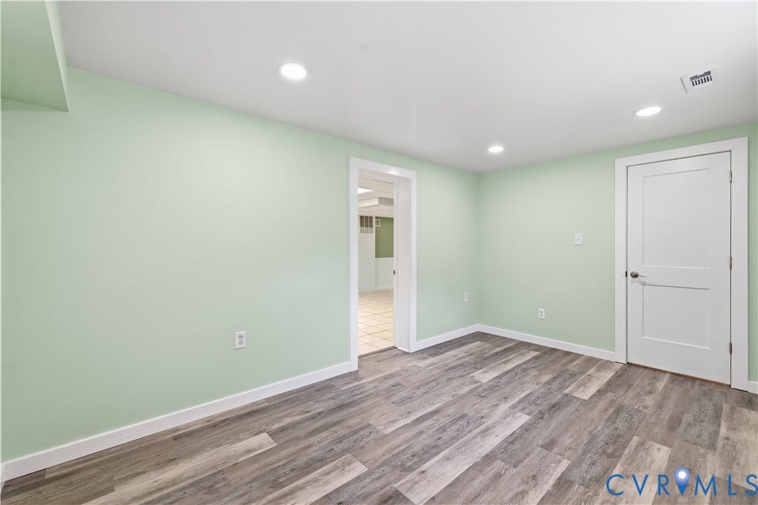 Bright, freshly painted 2nd primary room featuring soft sage-green walls, recessed ceiling lighting, and warm wood-finish flooring throughout