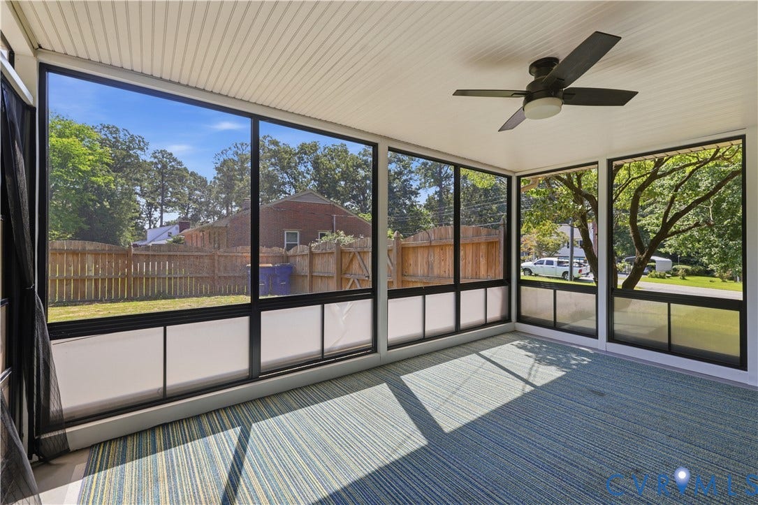 Enclosed porch with a ceiling fan, full-height windows, and a textured carpet