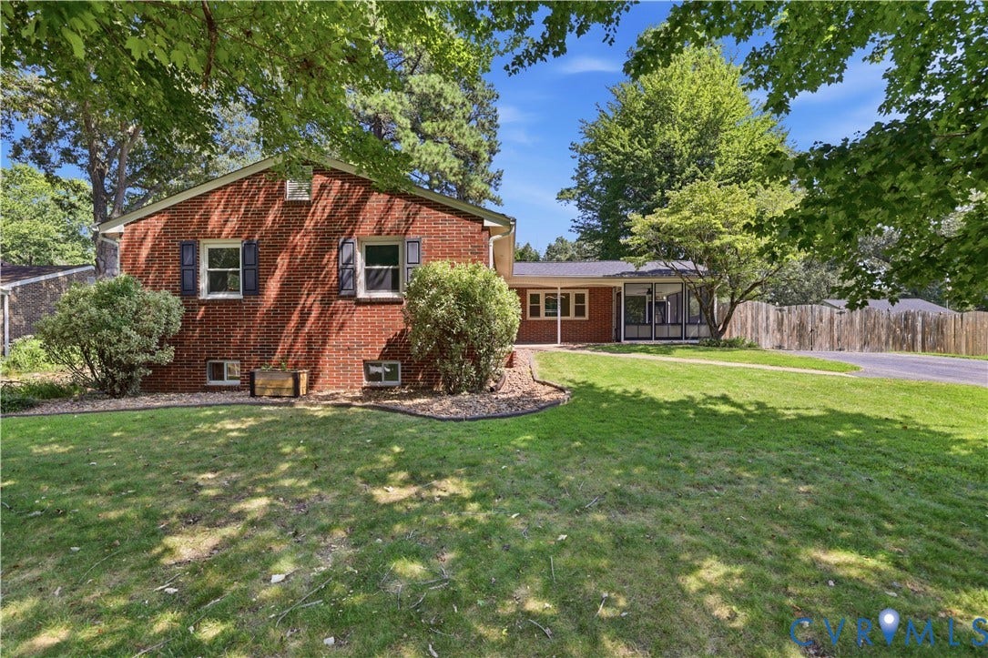 Brick exterior featuring a screened porch and a manicured lawn