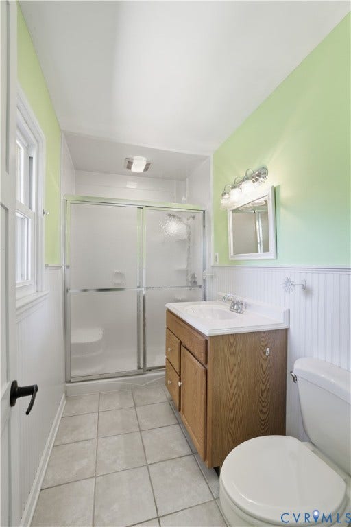 Spa-inspired bathroom featuring a tile floor, wood-finish vanity with integrated sink, chrome fixtures, and a frameless glass-enclosed shower