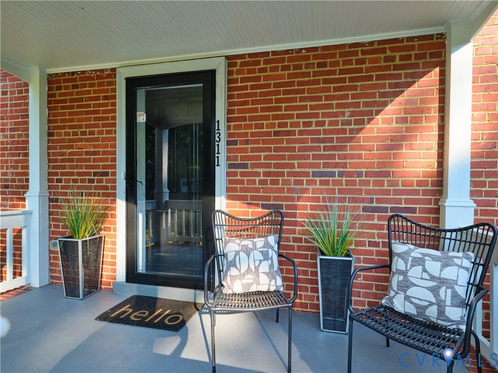 1311 Santa Rosa Road, Henrico, VA 23229 Brick exterior with a covered porch featuring beadboard ceiling, white support columns, and a black storm door