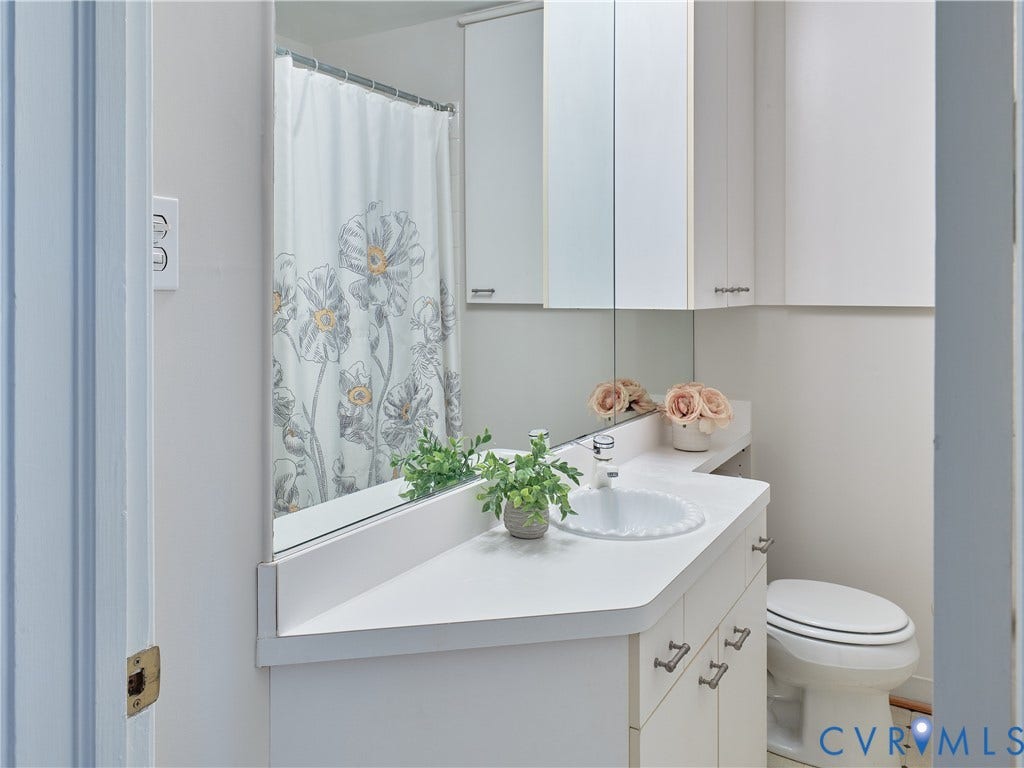 1311 Santa Rosa Road, Henrico, VA 23229 White vanity with integrated sink, white countertop, white wall-mounted storage cabinets, and a built-in toilet