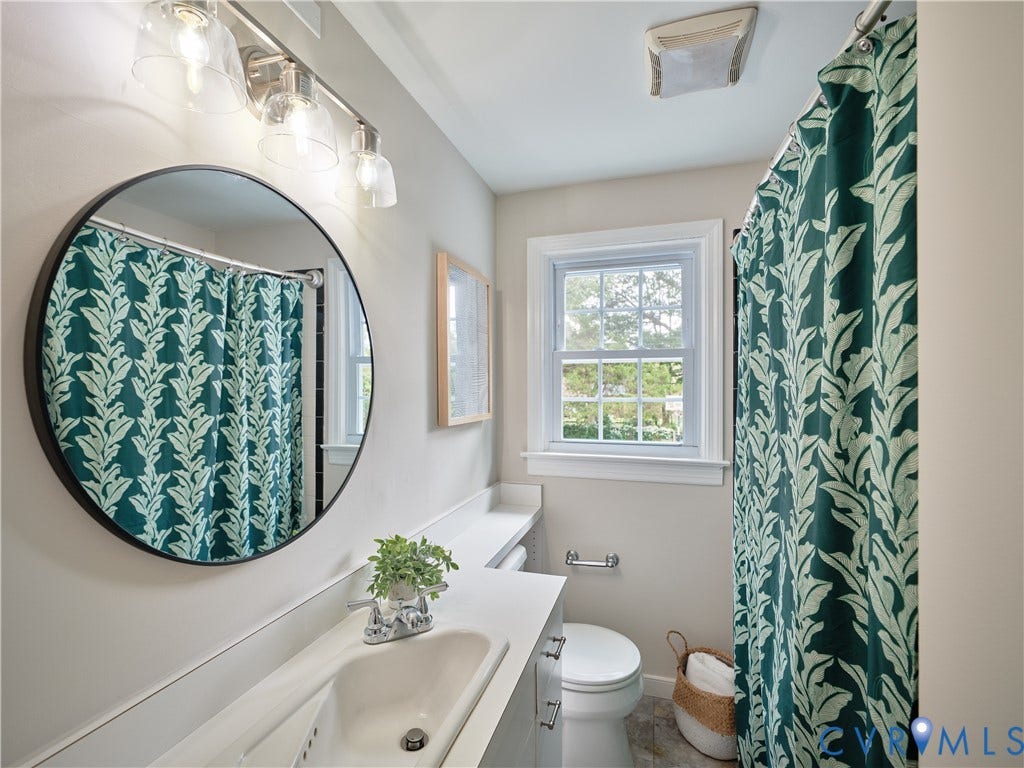 1311 Santa Rosa Road, Henrico, VA 23229 Bathroom featuring a single window, a vanity with an integrated sink, a circular mirror, and a three-light fixture