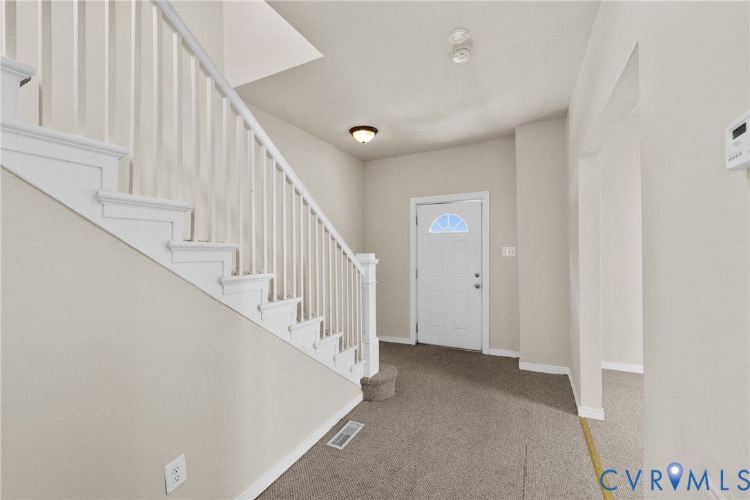 2314 Ingram Avenue, Richmond, VA 23224 White painted staircase with balusters, ceiling-mounted light fixture, and a front door with an arched glass insert